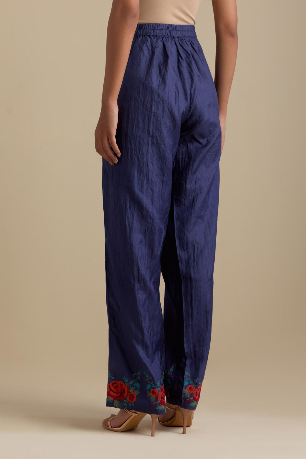 Blue silk straight pants with roses in thread embroidery at the hem.