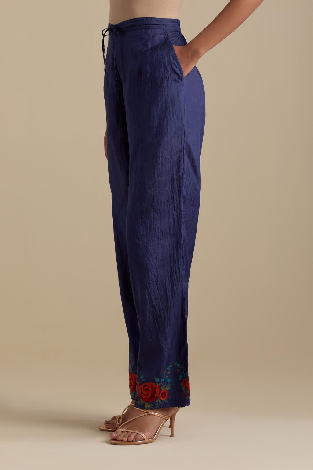 Blue silk straight pants with roses in thread embroidery at the hem.