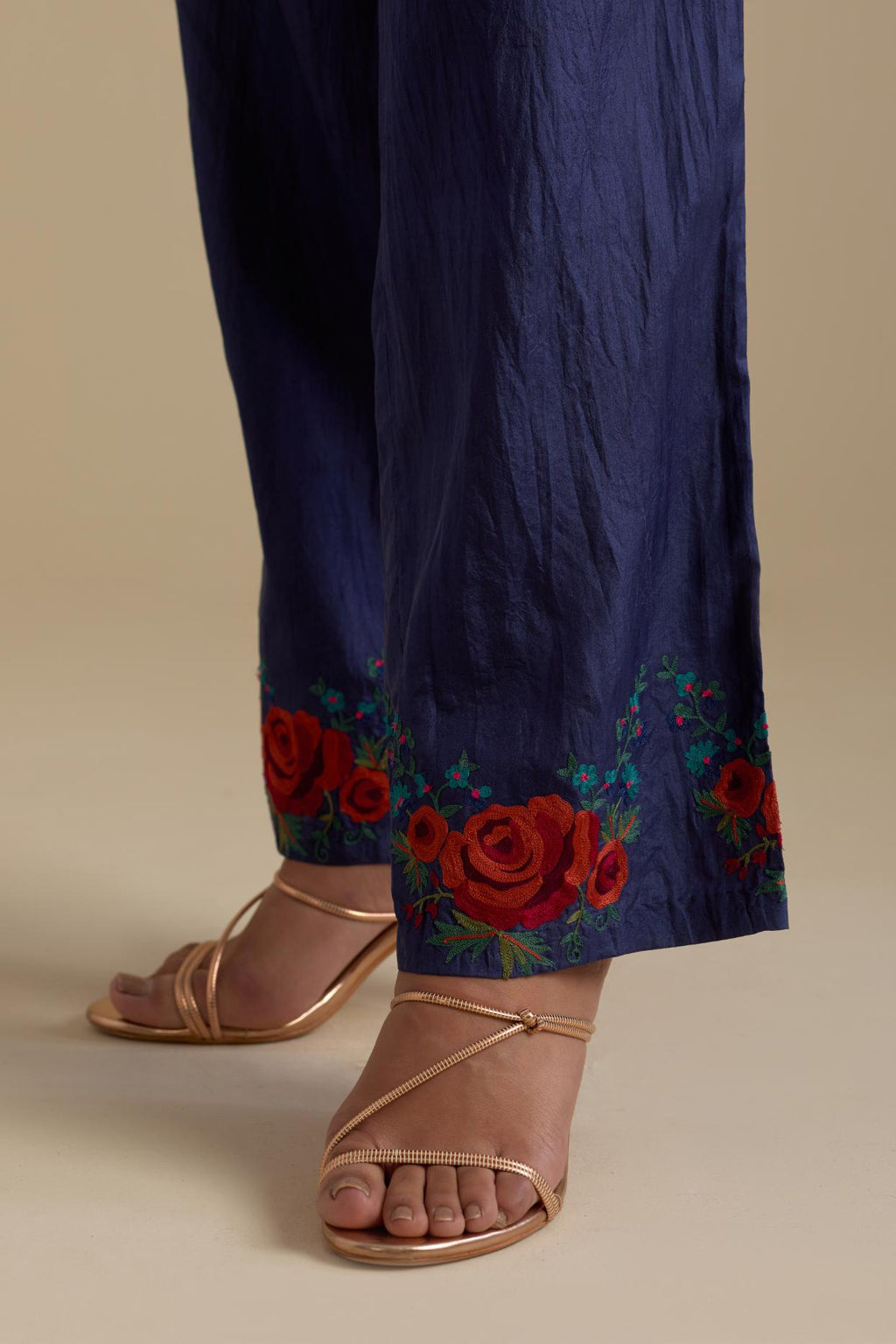 Blue silk straight pants with roses in thread embroidery at the hem.