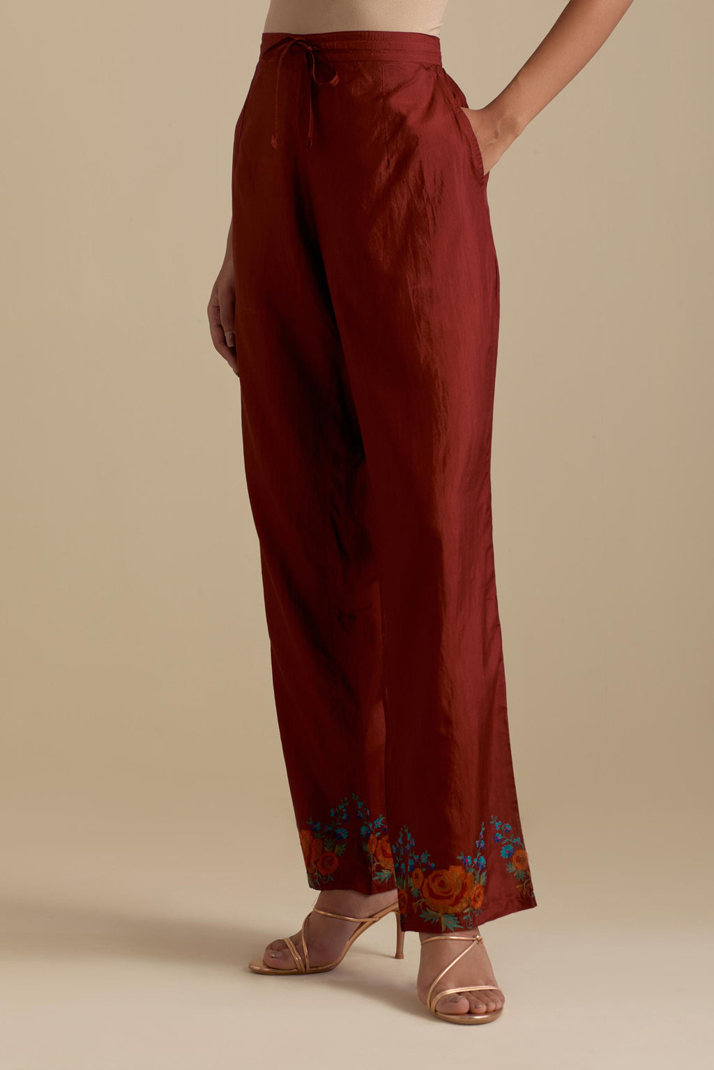 Maroon silk straight pants with roses in thread embroidery at the hem.