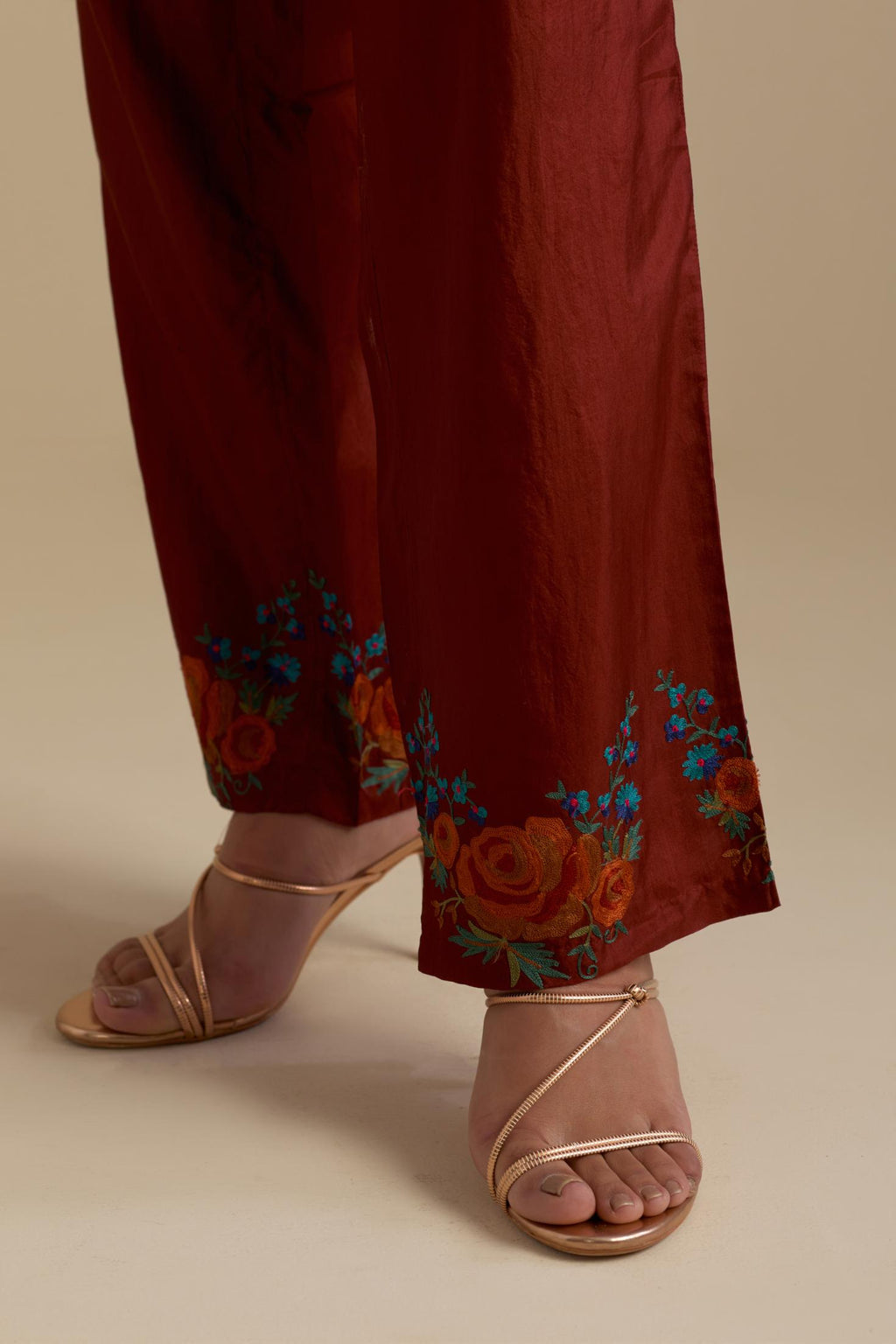 Maroon silk straight pants with roses in thread embroidery at the hem.