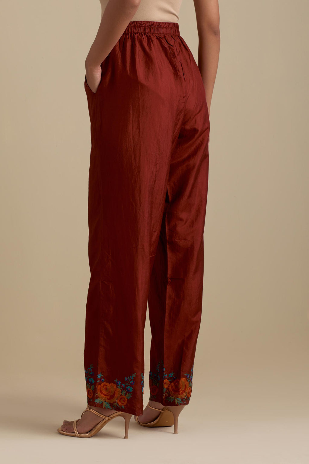 Maroon silk straight pants with roses in thread embroidery at the hem.