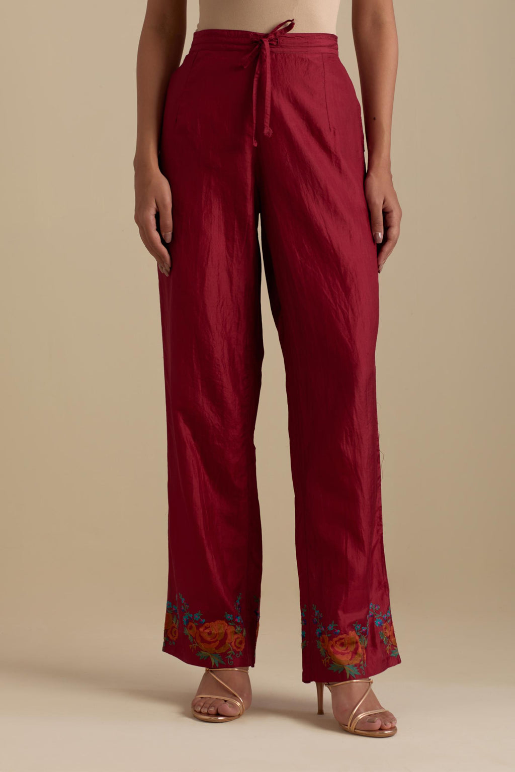 Barn red silk straight pants with roses in thread embroidery at the hem.