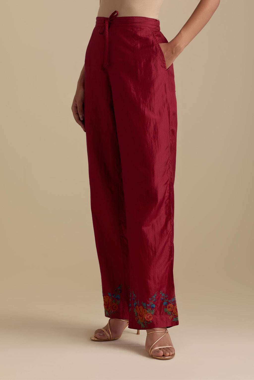 Barn red silk straight pants with roses in thread embroidery at the hem.