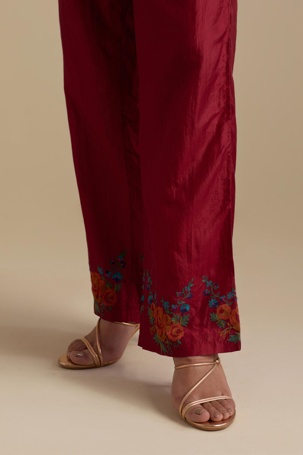 Barn red silk straight pants with roses in thread embroidery at the hem.