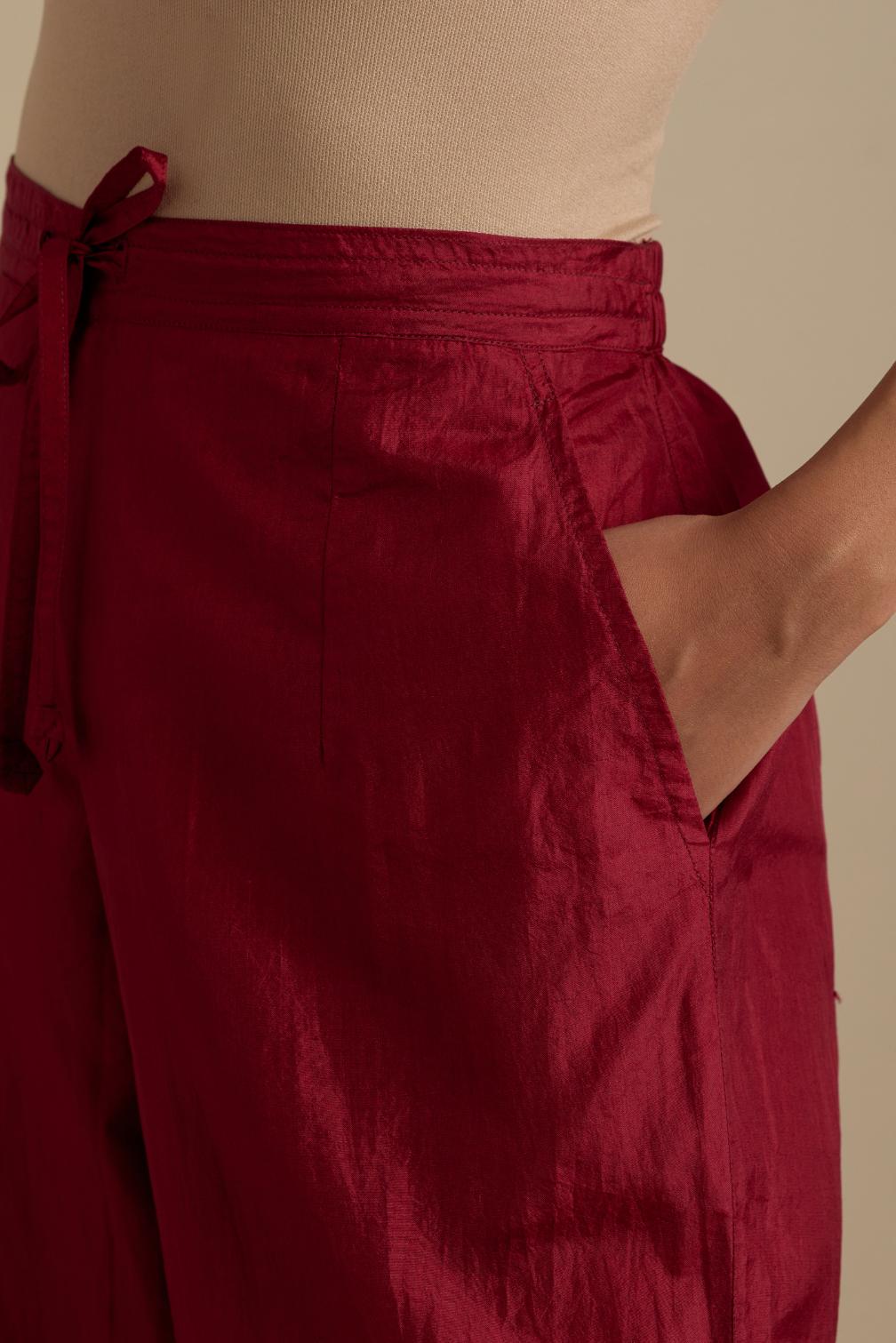 Barn red silk straight pants with roses in thread embroidery at the hem.