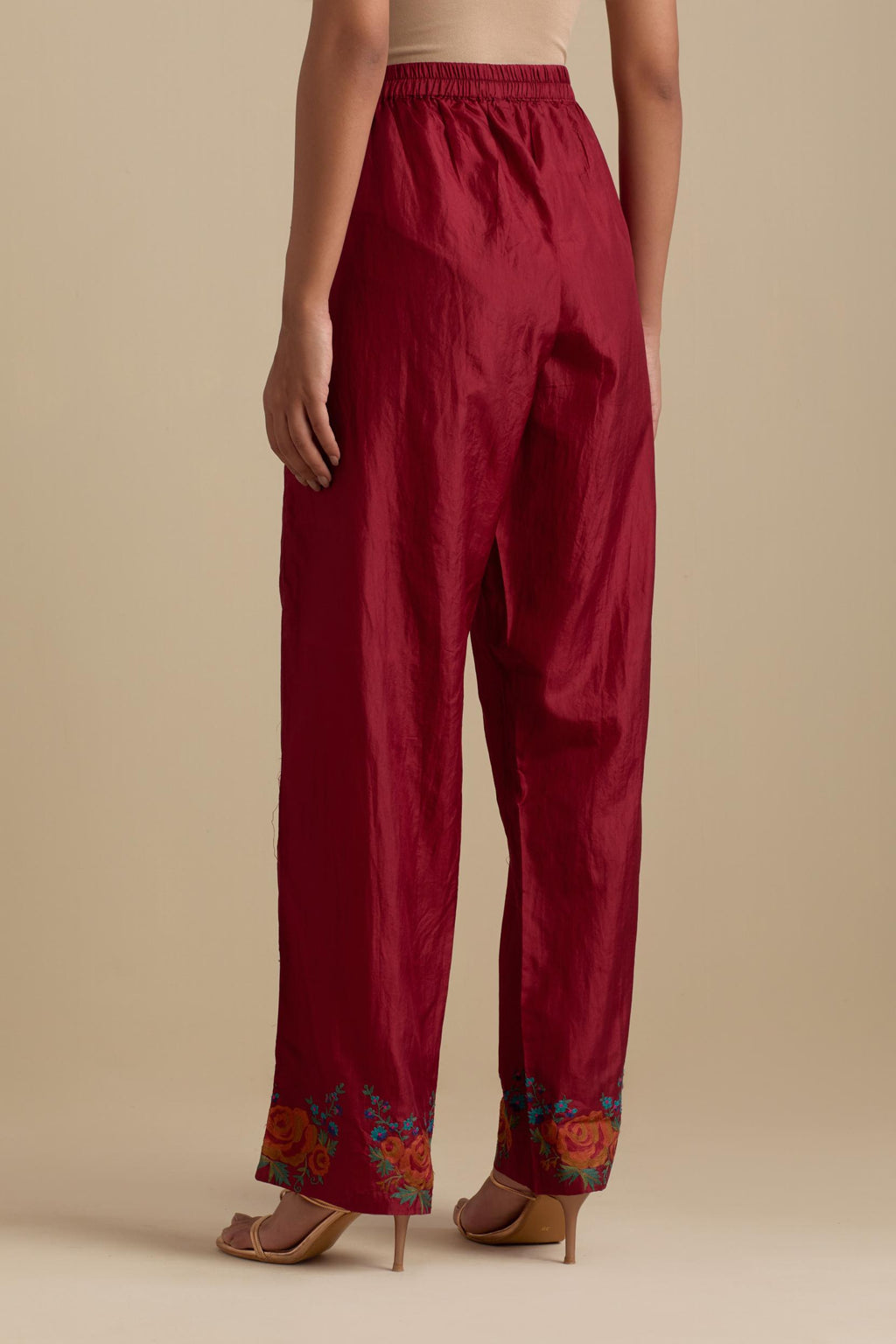 Barn red silk straight pants with roses in thread embroidery at the hem.