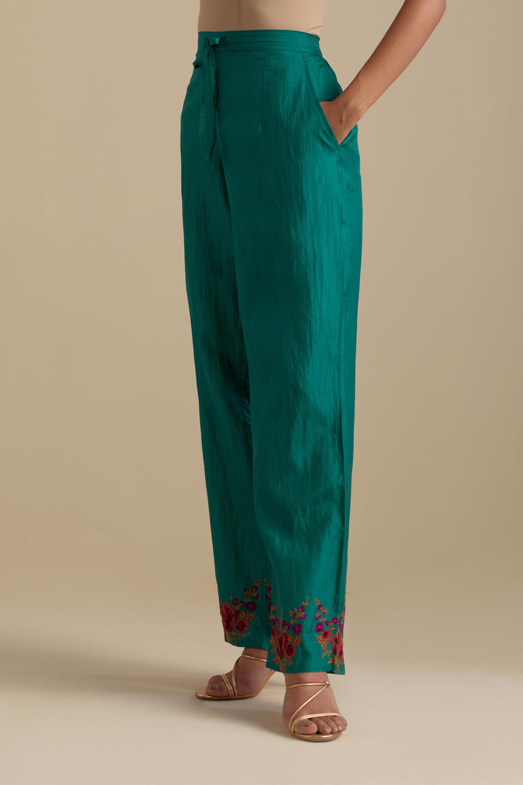 Persian green silk straight pants with roses in thread embroidery at the hem.