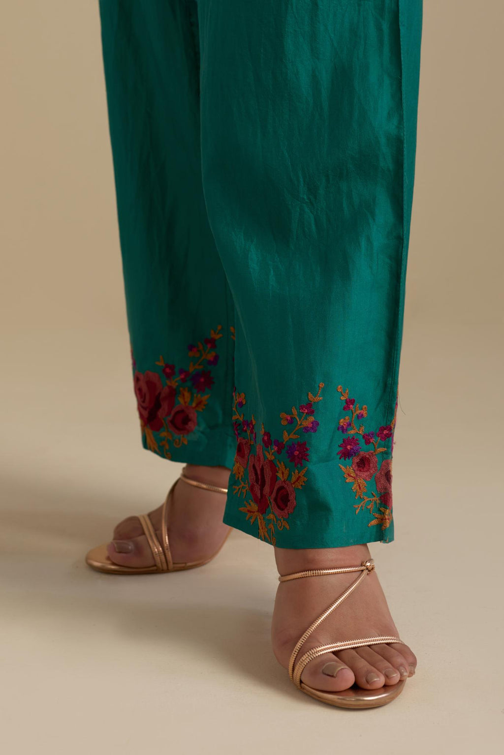 Persian green silk straight pants with roses in thread embroidery at the hem.