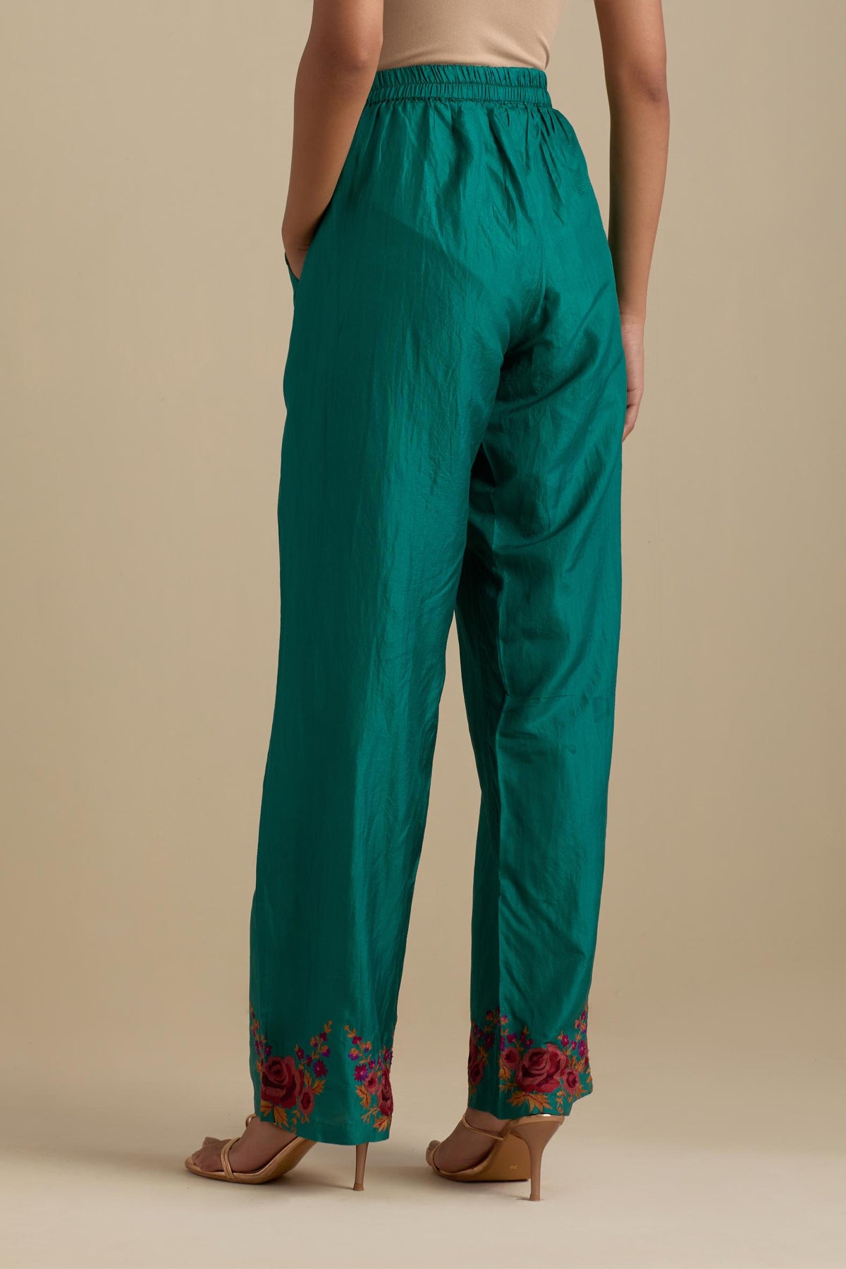 Persian green silk straight pants with roses in thread embroidery at the hem.