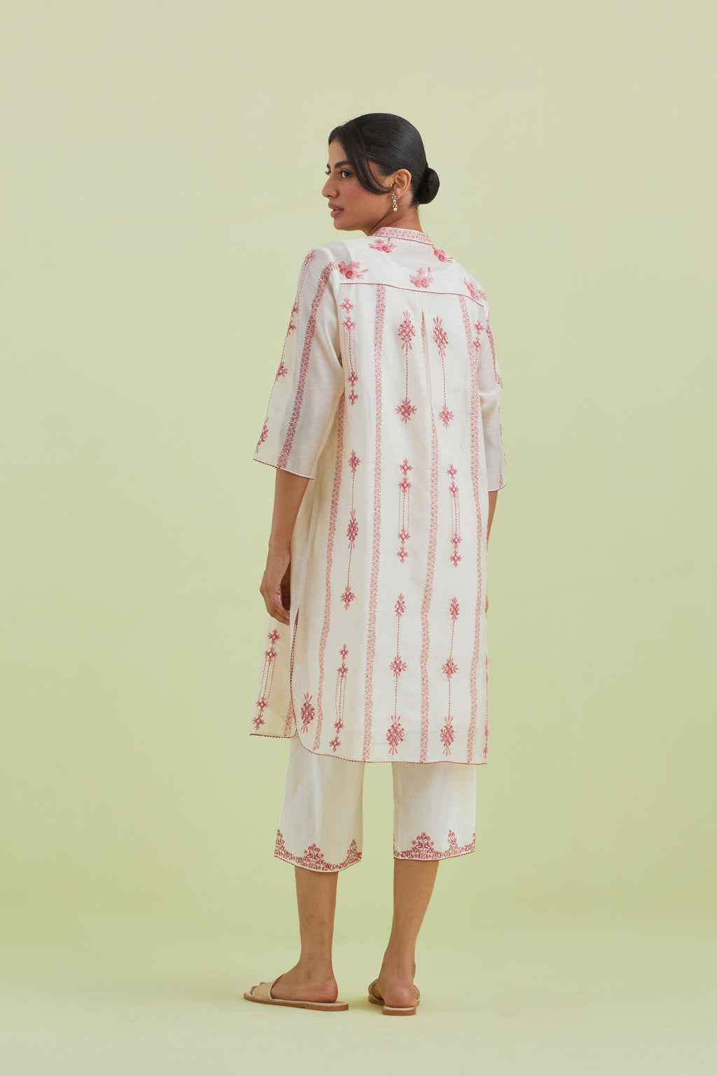 Pink and off-white hand block printed silk chanderi straight short kurta with thread and mirror embroidery along with kantha work, paired with off white straight ankle length pants with pink colored hand-block printed border at hem.