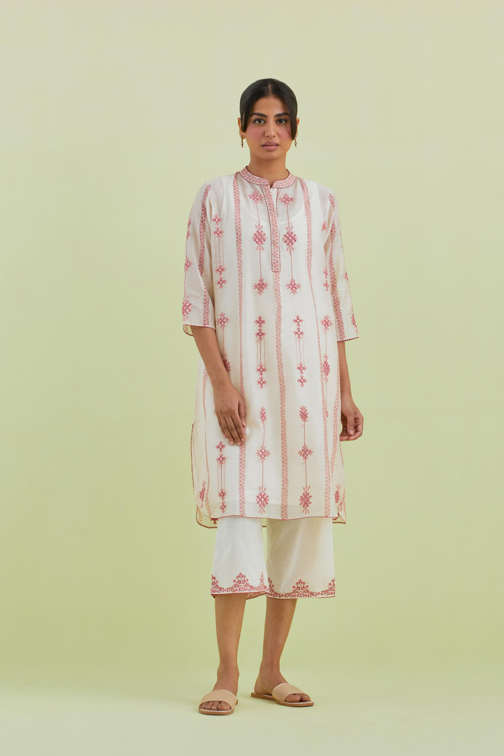 Pink and off-white hand block printed silk chanderi straight short kurta with thread and mirror embroidery along with kantha work, paired with off white straight ankle length pants with pink colored hand-block printed border at hem.