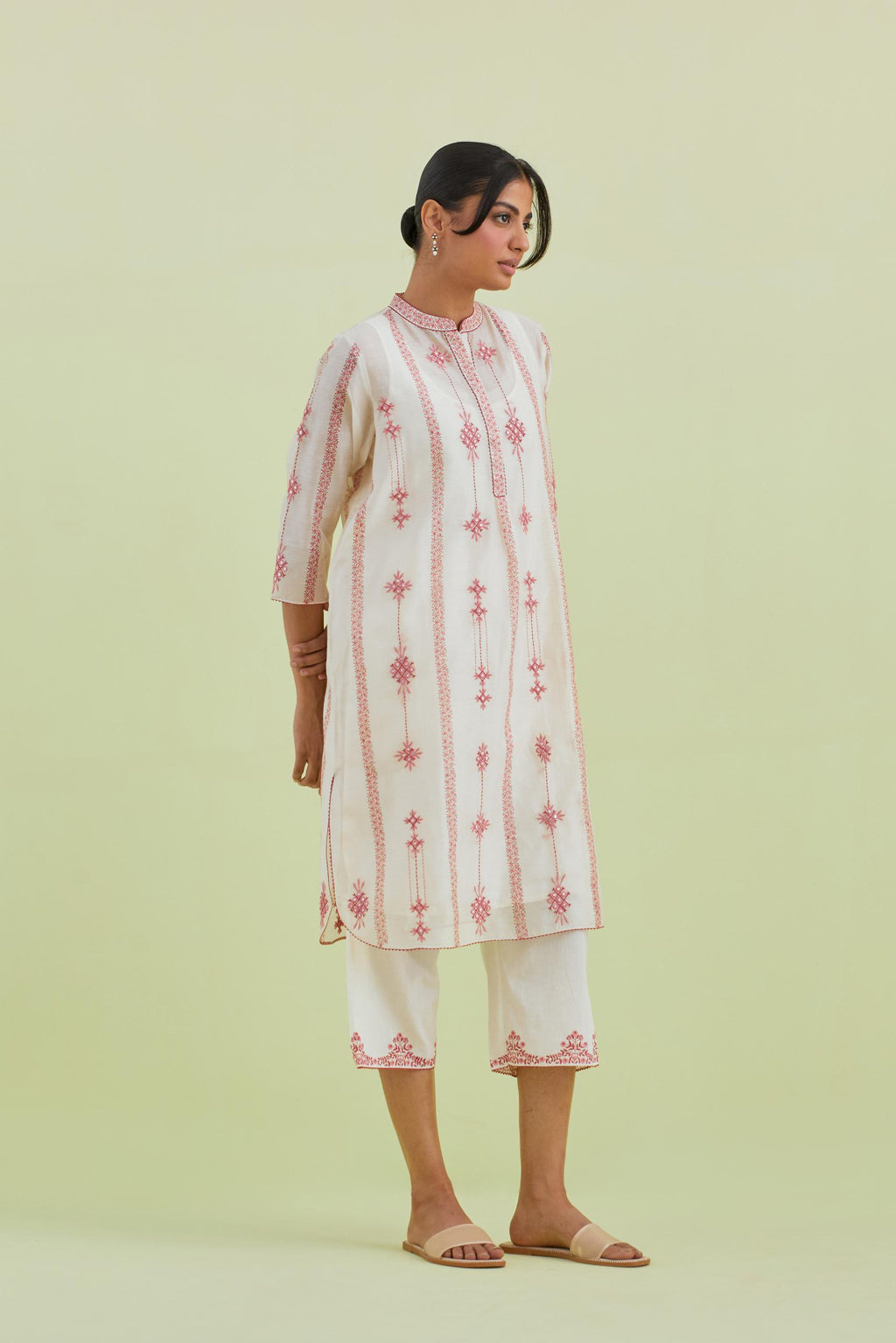 Pink and off-white hand block printed silk chanderi straight short kurta with thread and mirror embroidery along with kantha work, paired with off white straight ankle length pants with pink colored hand-block printed border at hem.