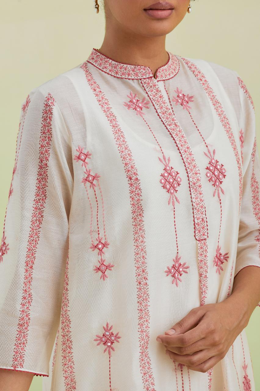 Pink and off-white hand block printed silk chanderi straight short kurta with thread and mirror embroidery along with kantha work, paired with off white straight ankle length pants with pink colored hand-block printed border at hem.