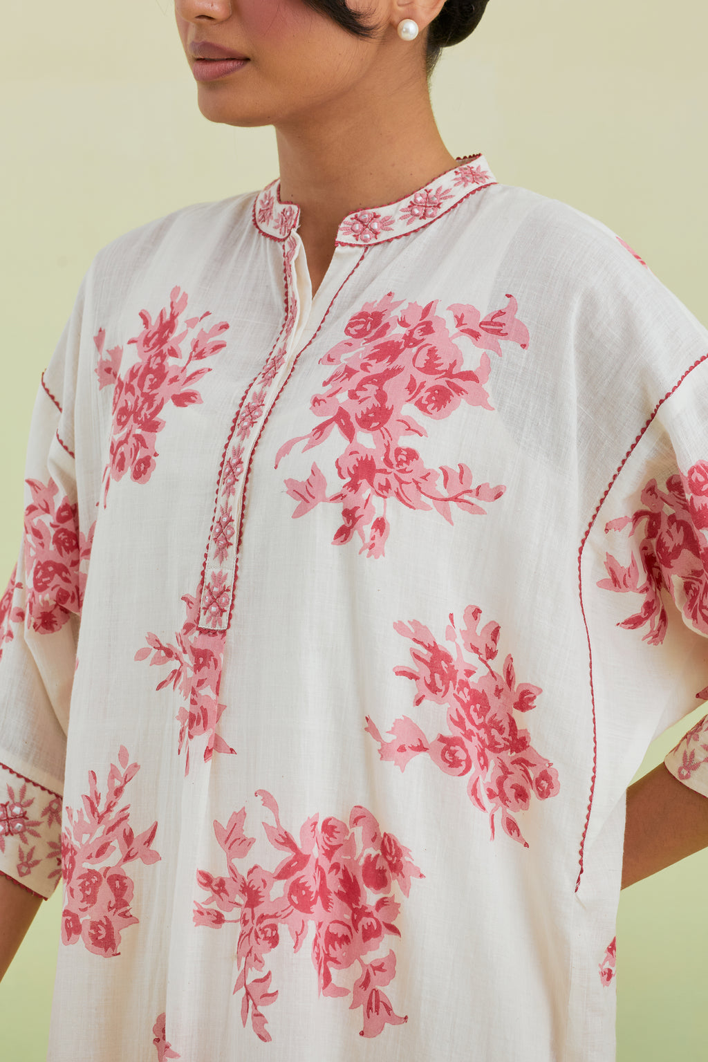 Pink and off-white hand block printed cotton easy fit short kurta with thread and mirror embroidery, paired with off white straight ankle length pants with all-over pink colored floral boota hand-block print.