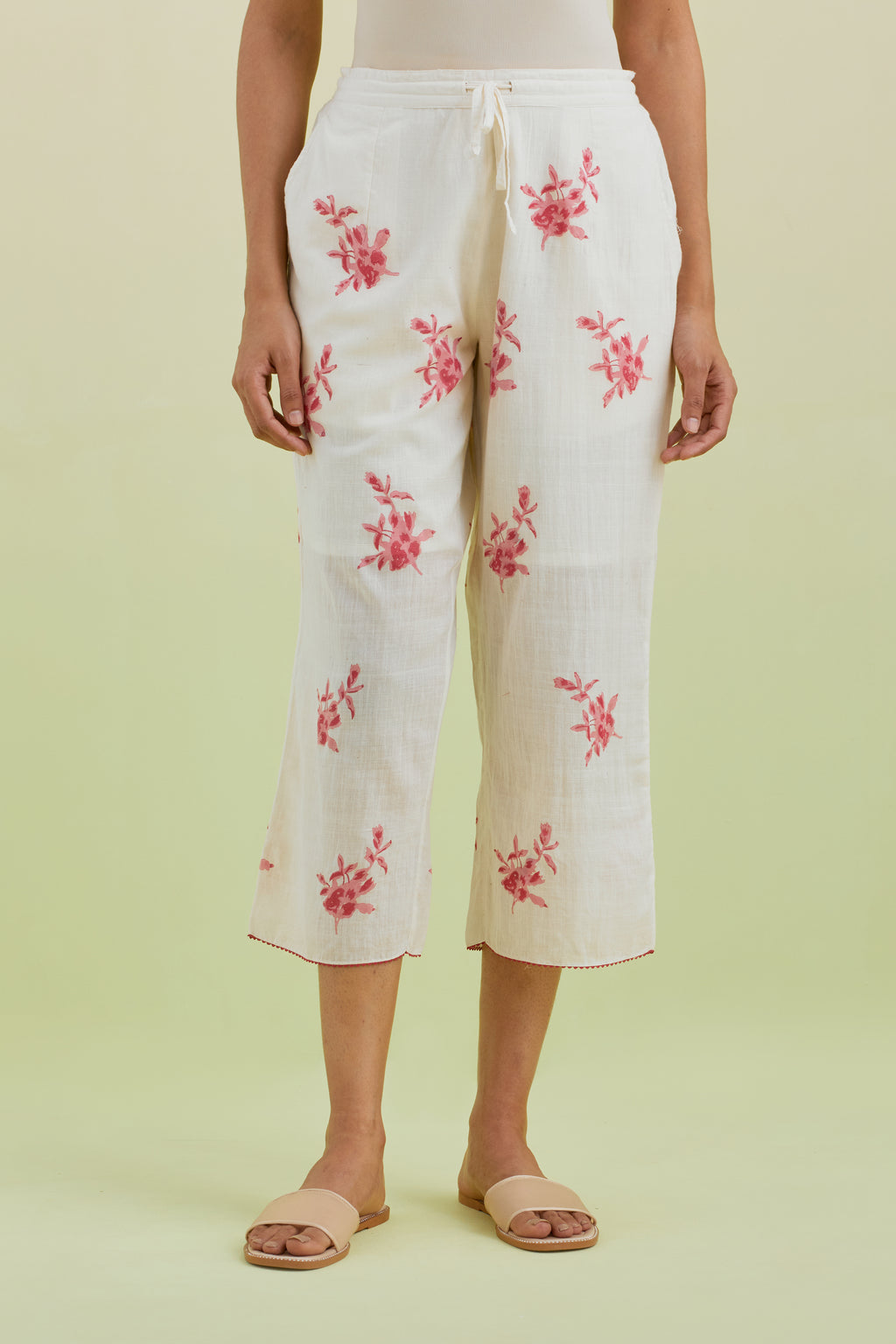 Off white straight ankle length pants with all-over pink colored floral boota hand-block print.