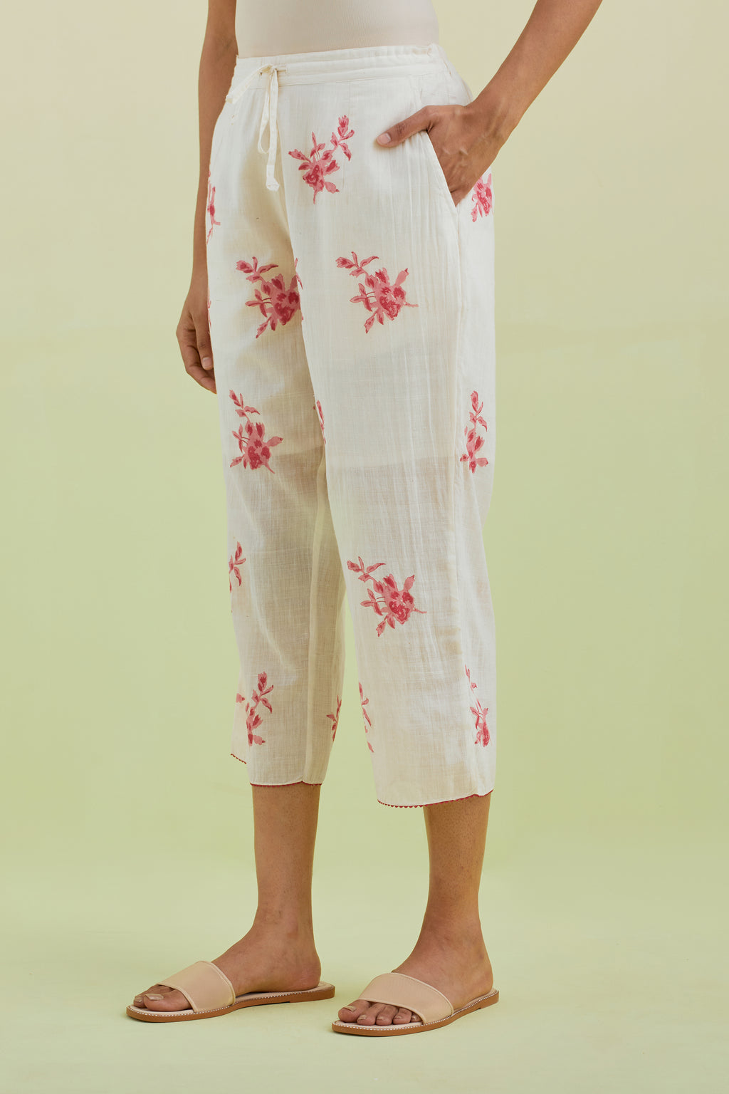 Off white straight ankle length pants with all-over pink colored floral boota hand-block print.