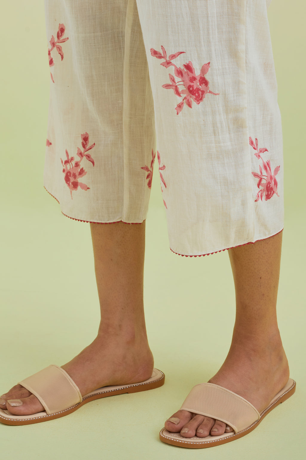 Off white straight ankle length pants with all-over pink colored floral boota hand-block print.