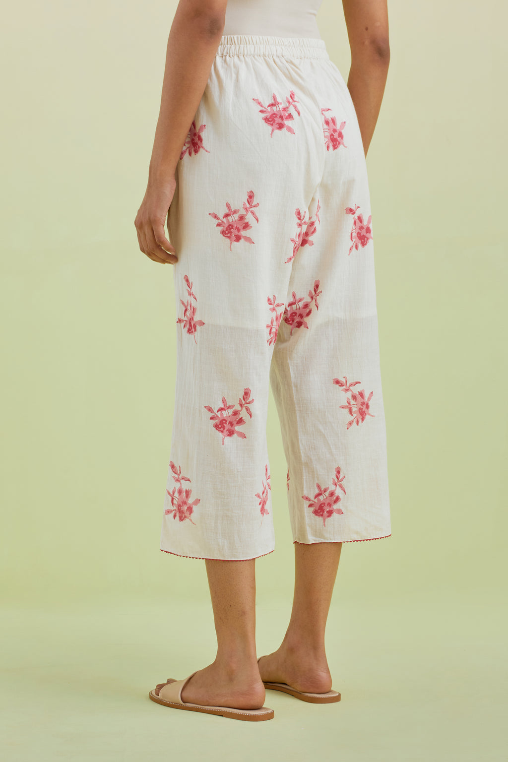 Off white straight ankle length pants with all-over pink colored floral boota hand-block print.