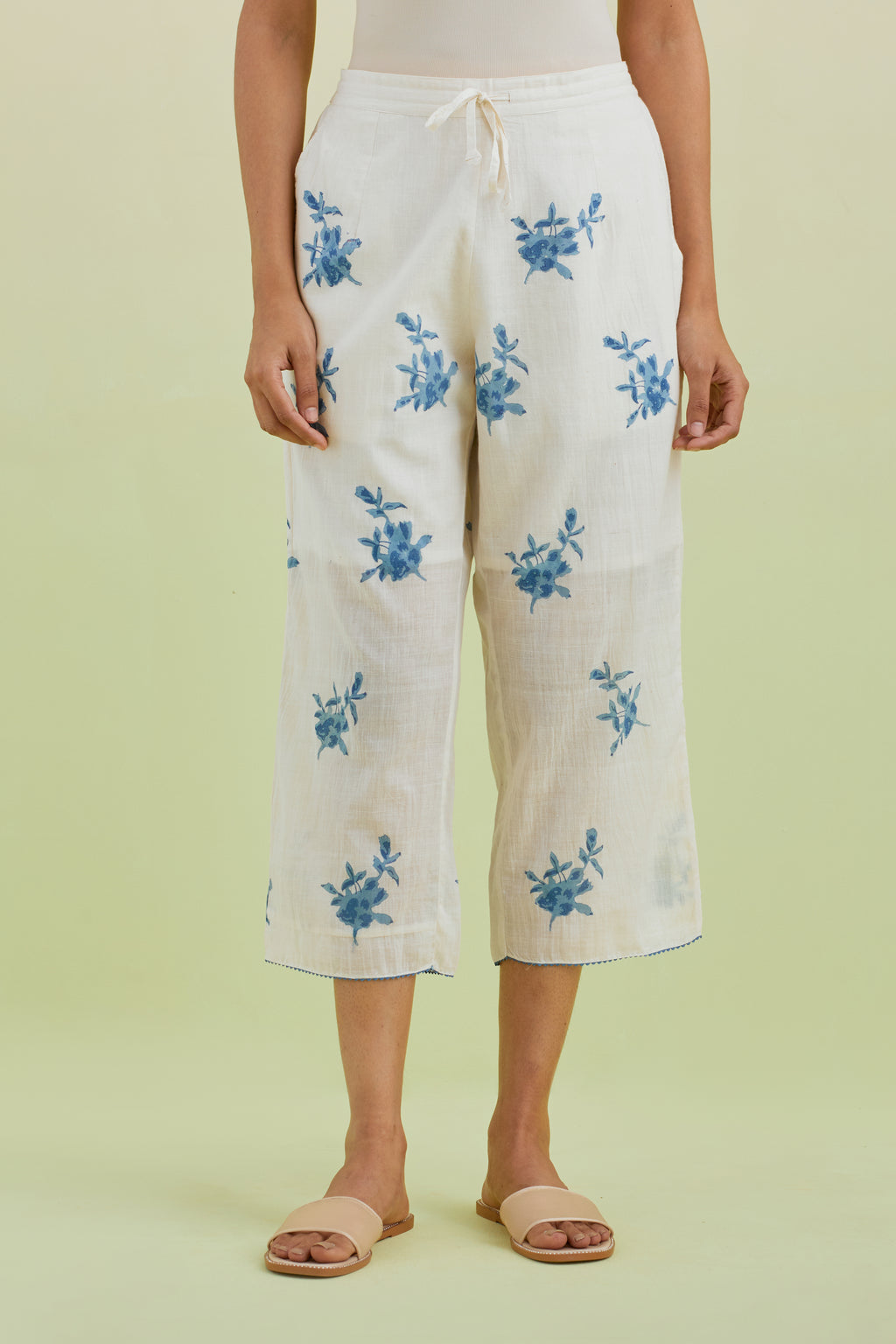 Off white straight ankle length pants with all-over blue colored floral boota hand-block print.