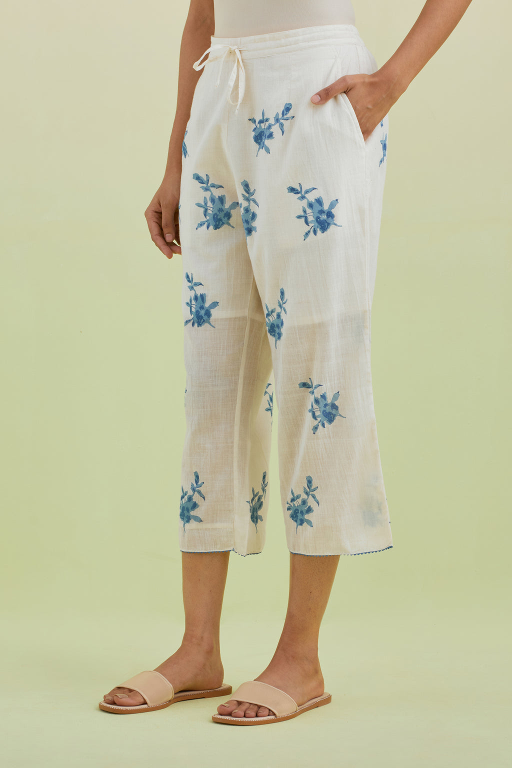 Off white straight ankle length pants with all-over blue colored floral boota hand-block print.