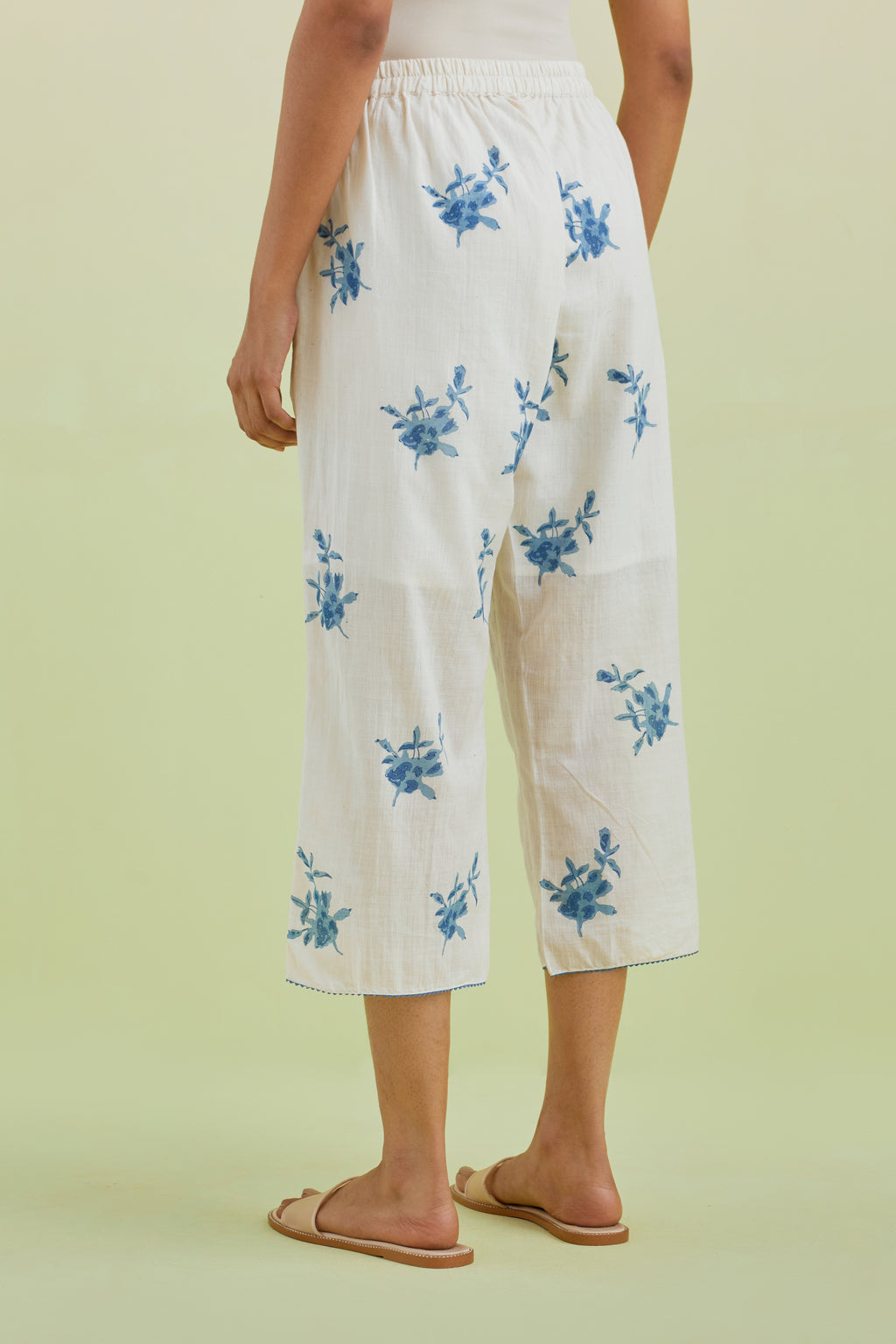 Off white straight ankle length pants with all-over blue colored floral boota hand-block print.