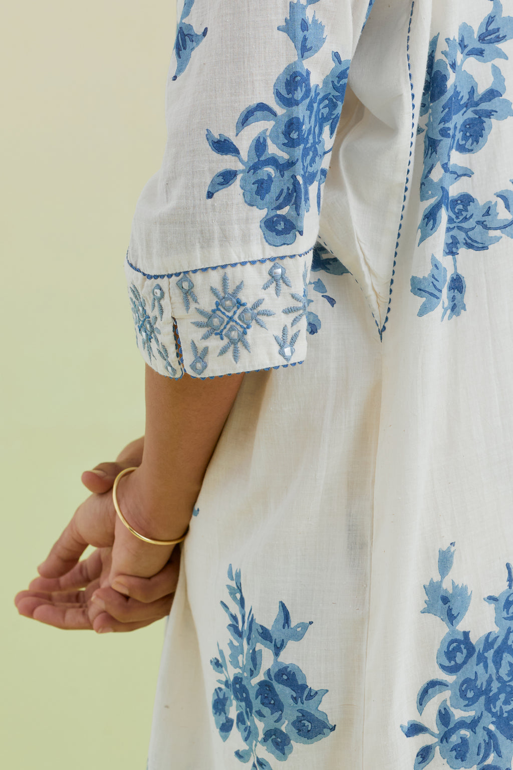 Blue and off-white hand block printed cotton easy fit short kurta with thread and mirror embroidery, paired with off white straight ankle length pants with all-over blue colored floral boota hand-block print.