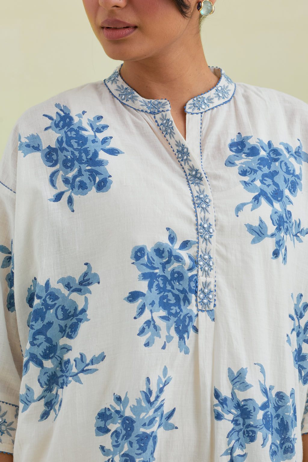 Blue and off-white hand block printed cotton easy fit short kurta with thread and mirror embroidery, paired with off white straight ankle length pants with all-over blue colored floral boota hand-block print.