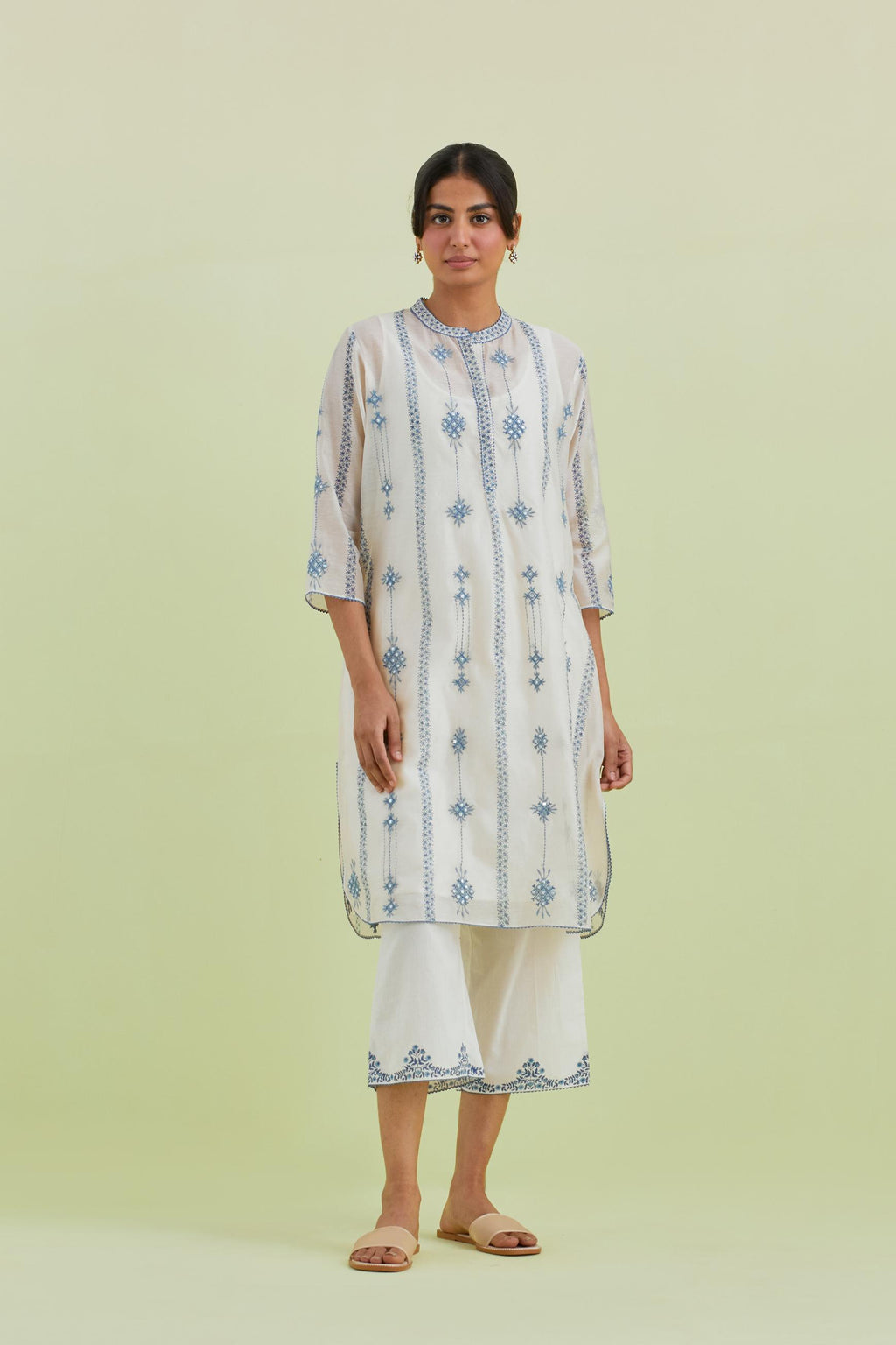 Blue and off-white hand block printed silk chanderi straight short kurta with thread and mirror embroidery along with kantha work, paired with off white straight ankle length pants with blue colored hand-block printed border at hem.