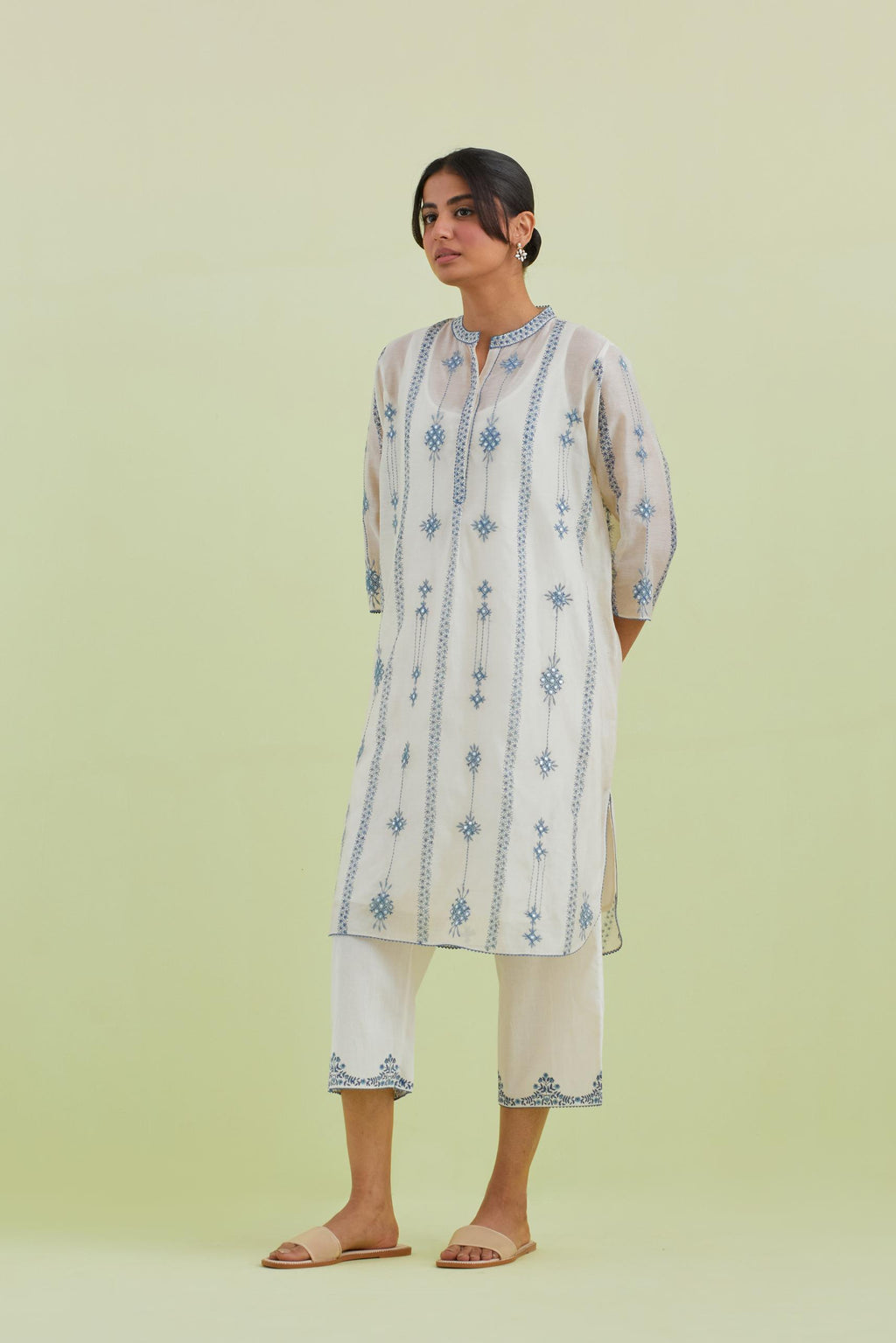 Blue and off-white hand block printed silk chanderi straight short kurta with thread and mirror embroidery along with kantha work, paired with off white straight ankle length pants with blue colored hand-block printed border at hem.