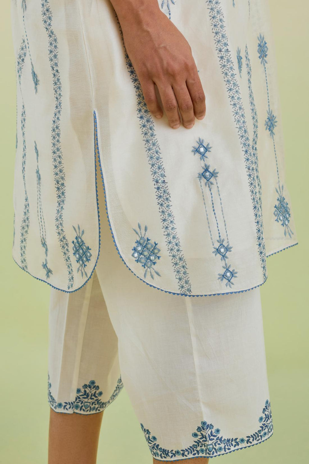 Blue and off-white hand block printed silk chanderi straight short kurta with thread and mirror embroidery along with kantha work, paired with off white straight ankle length pants with blue colored hand-block printed border at hem.