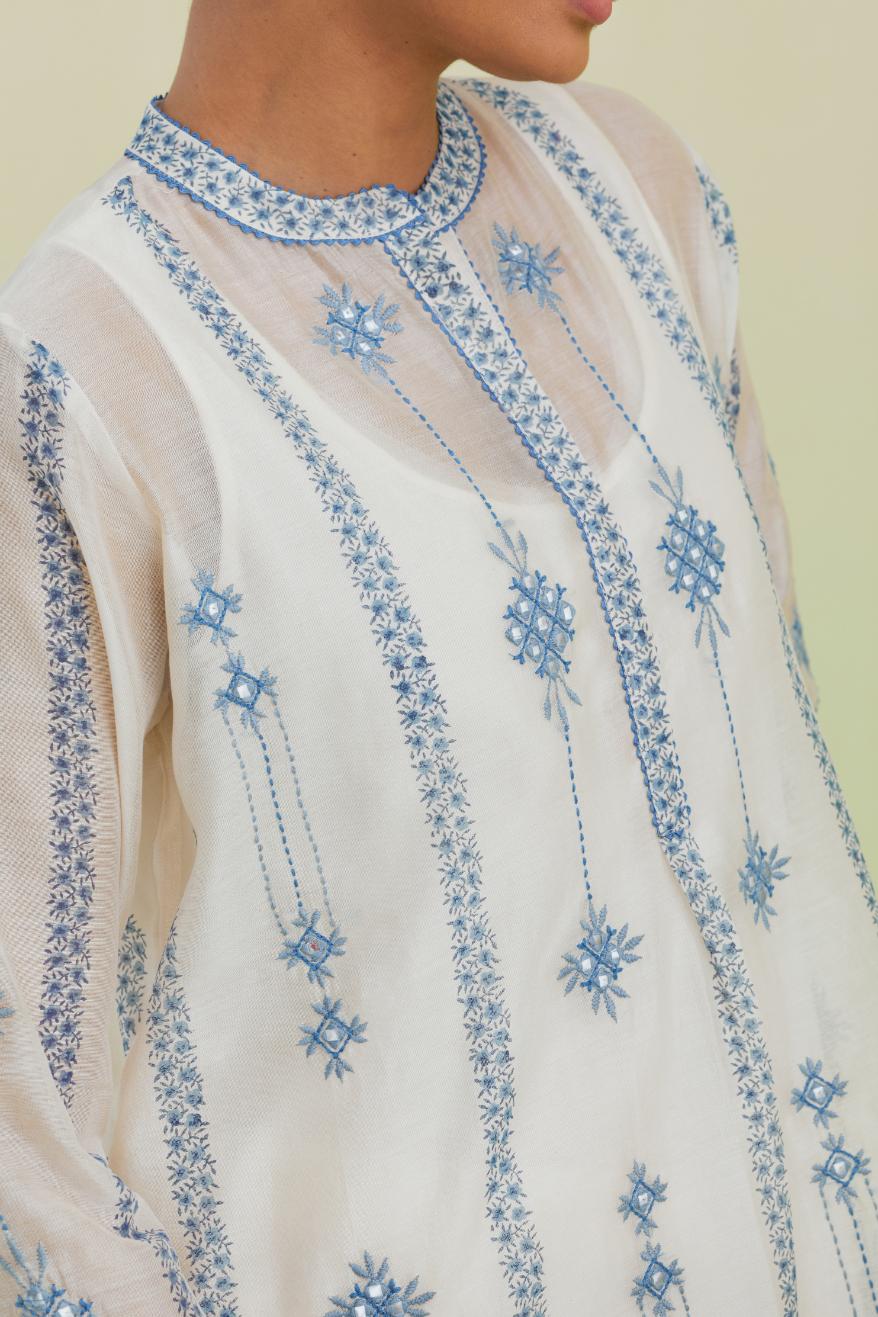 Blue and off-white hand block printed silk chanderi straight short kurta with thread and mirror embroidery along with kantha work, paired with off white straight ankle length pants with blue colored hand-block printed border at hem.