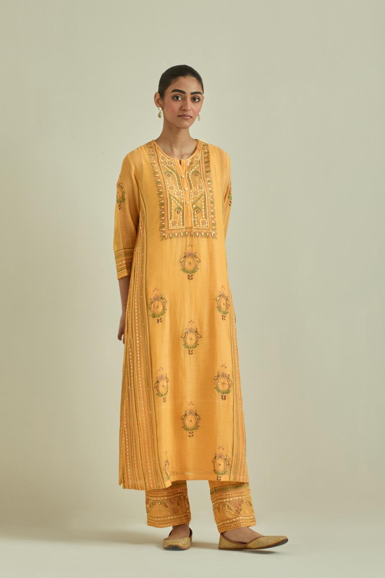 Yellow cotton chanderi straight kurta set with yoke and side panels. It has allover patchwork and silk thread embroidery, highlighted with mirror, sequins, tassels and braids.