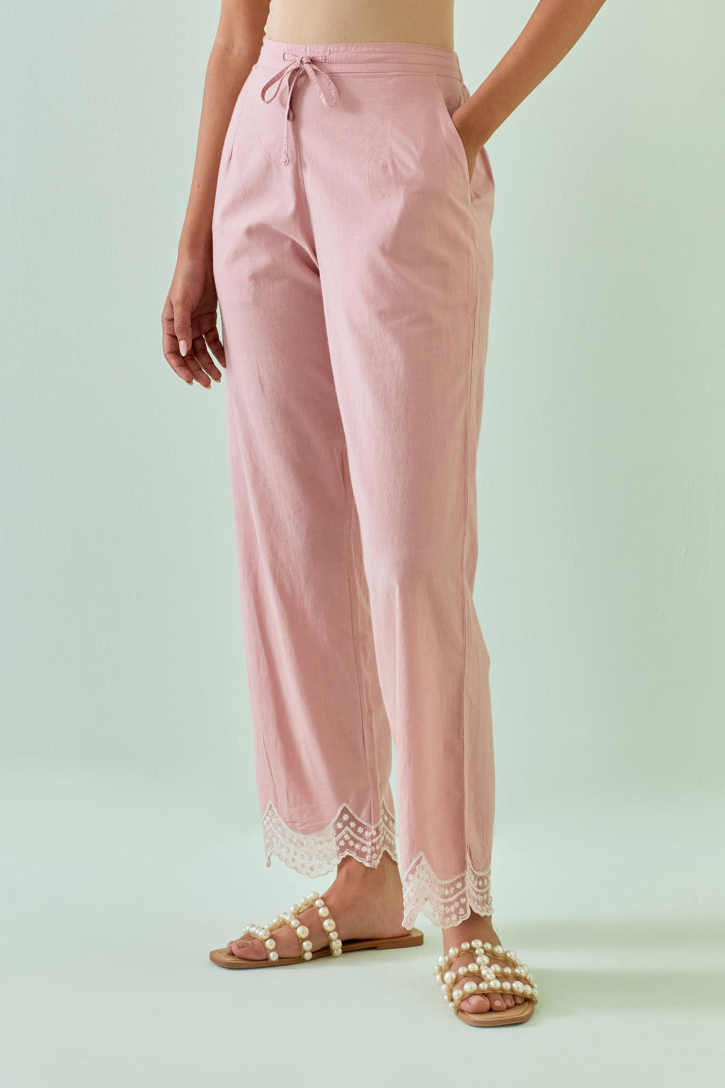 Pink straight pants with scalloped embroidery at bottom hem.