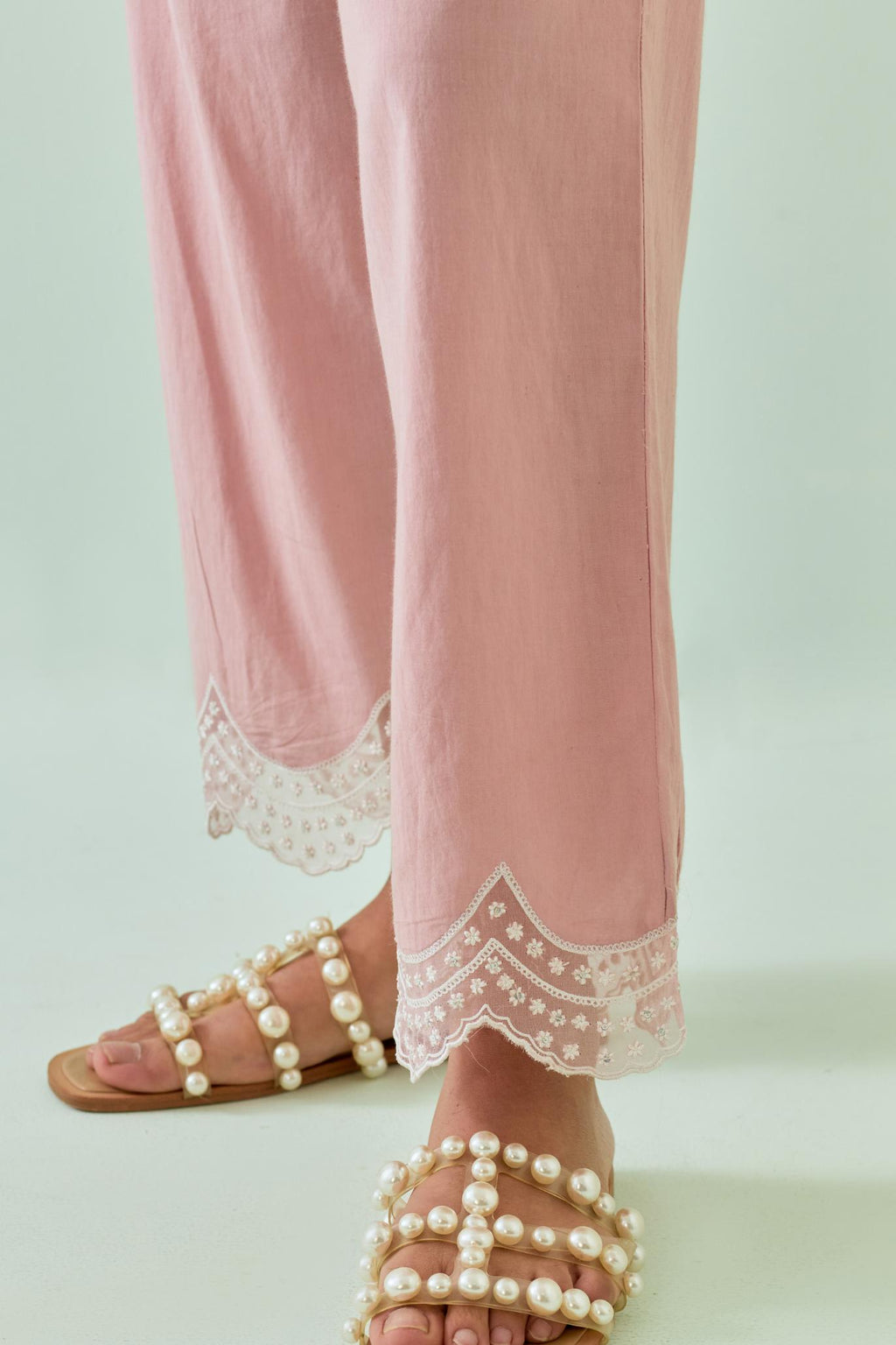 Pink straight pants with scalloped embroidery at bottom hem.