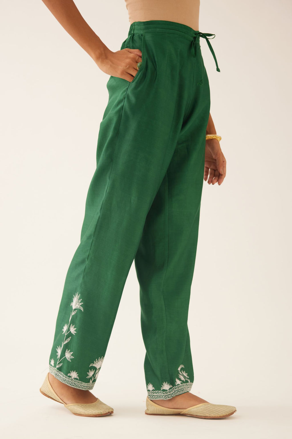Green silk chanderi straight pants with off white silk thread embroidery at hem.