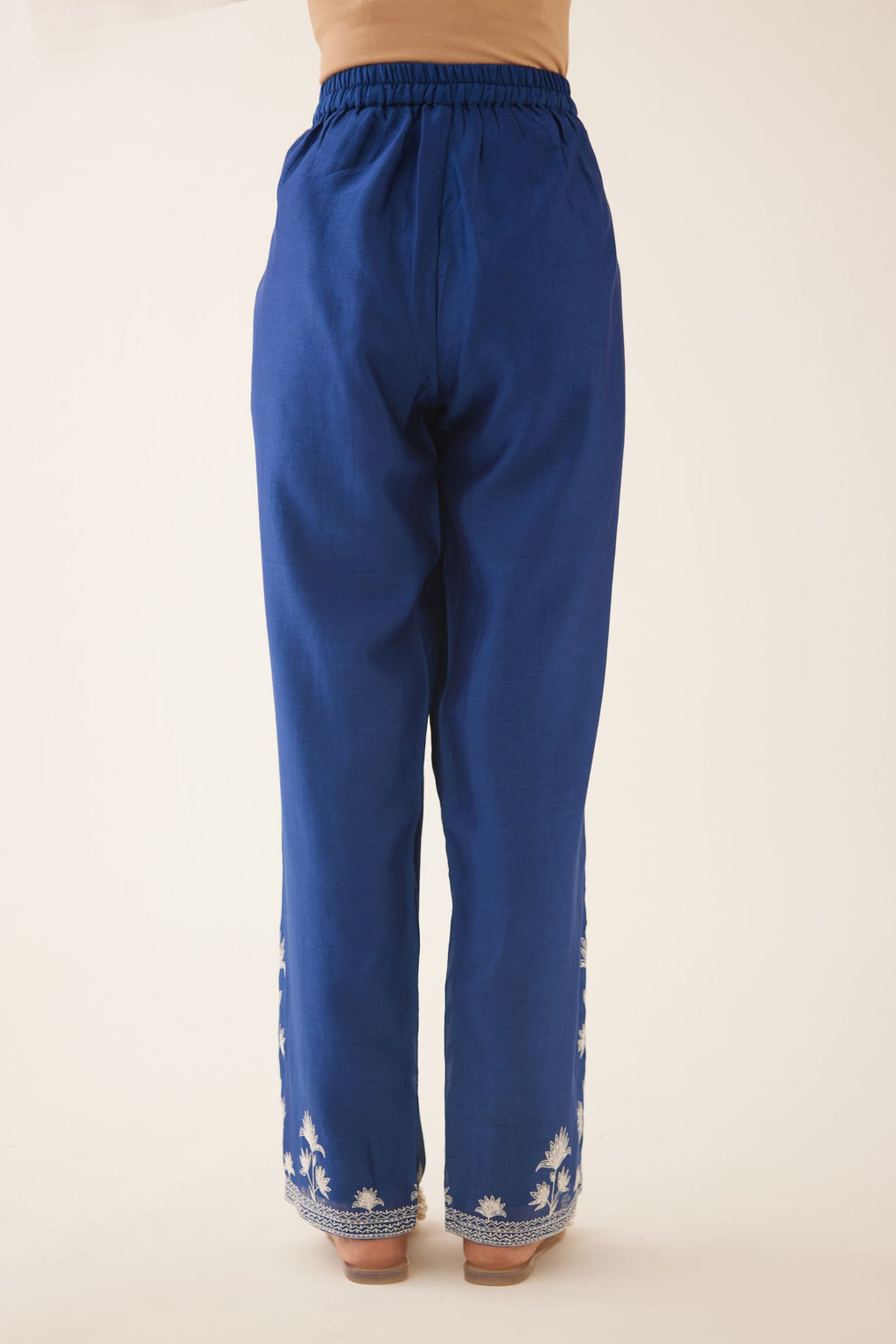 Blue silk chanderi straight pants with off white silk thread embroidery at hem.