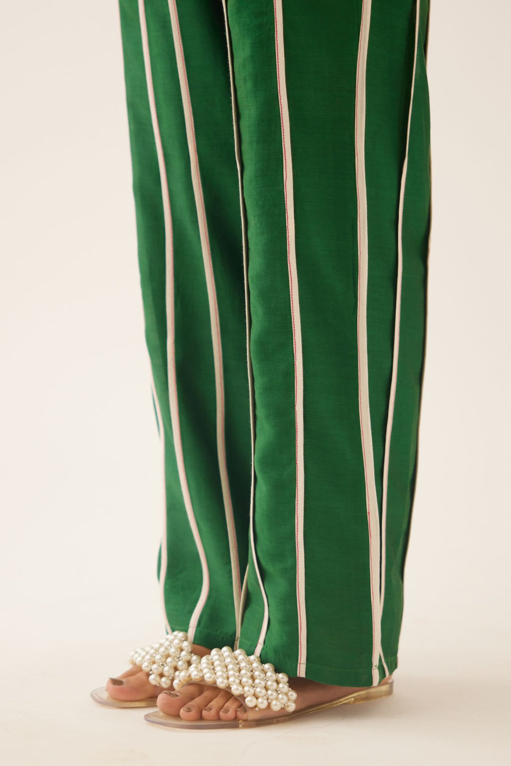 Green silk chanderi straight pants with vertical off white piping detail.