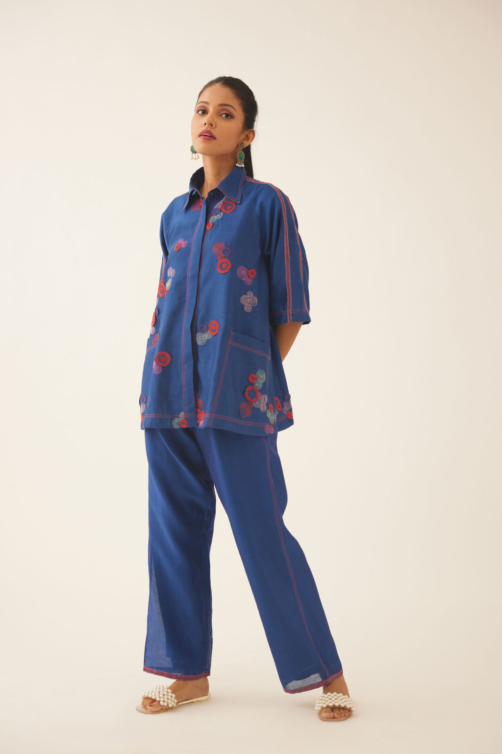 Blue silk chanderi A-line top with shirt collar and multi colored 3D spiral embroidery, paired with blue silk chanderi straight pants with quilted embroidery at hem.