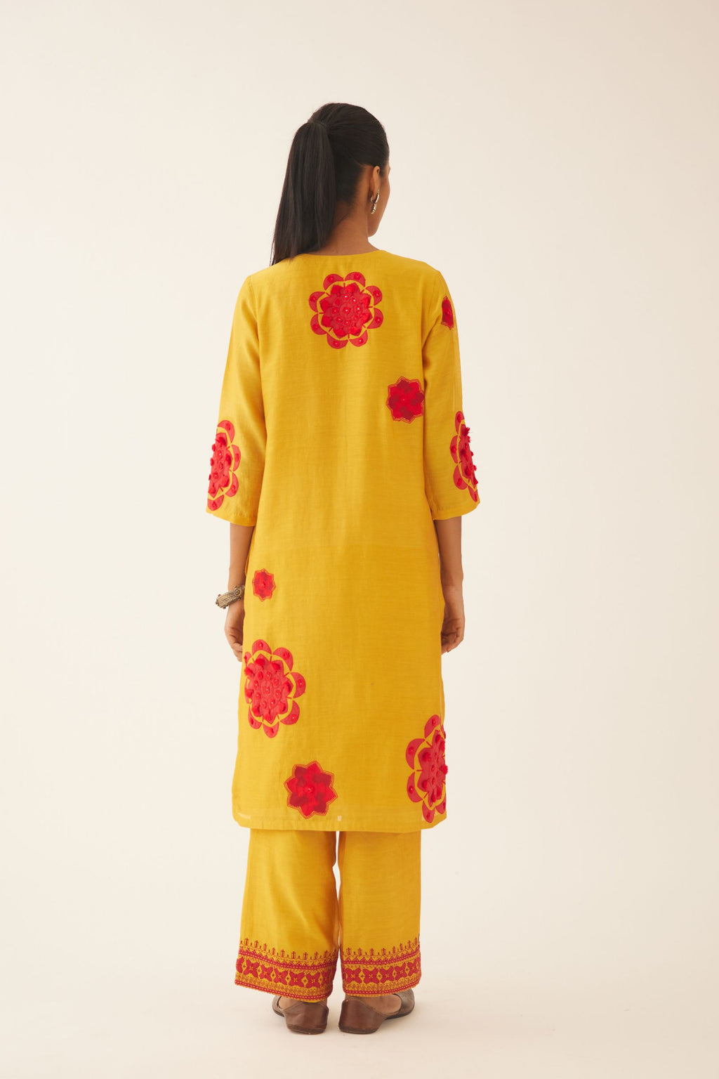 Yellow silk chanderi straight kurta set with 3/4th sleeve, highlighted with red patch, tassles & sequence work.