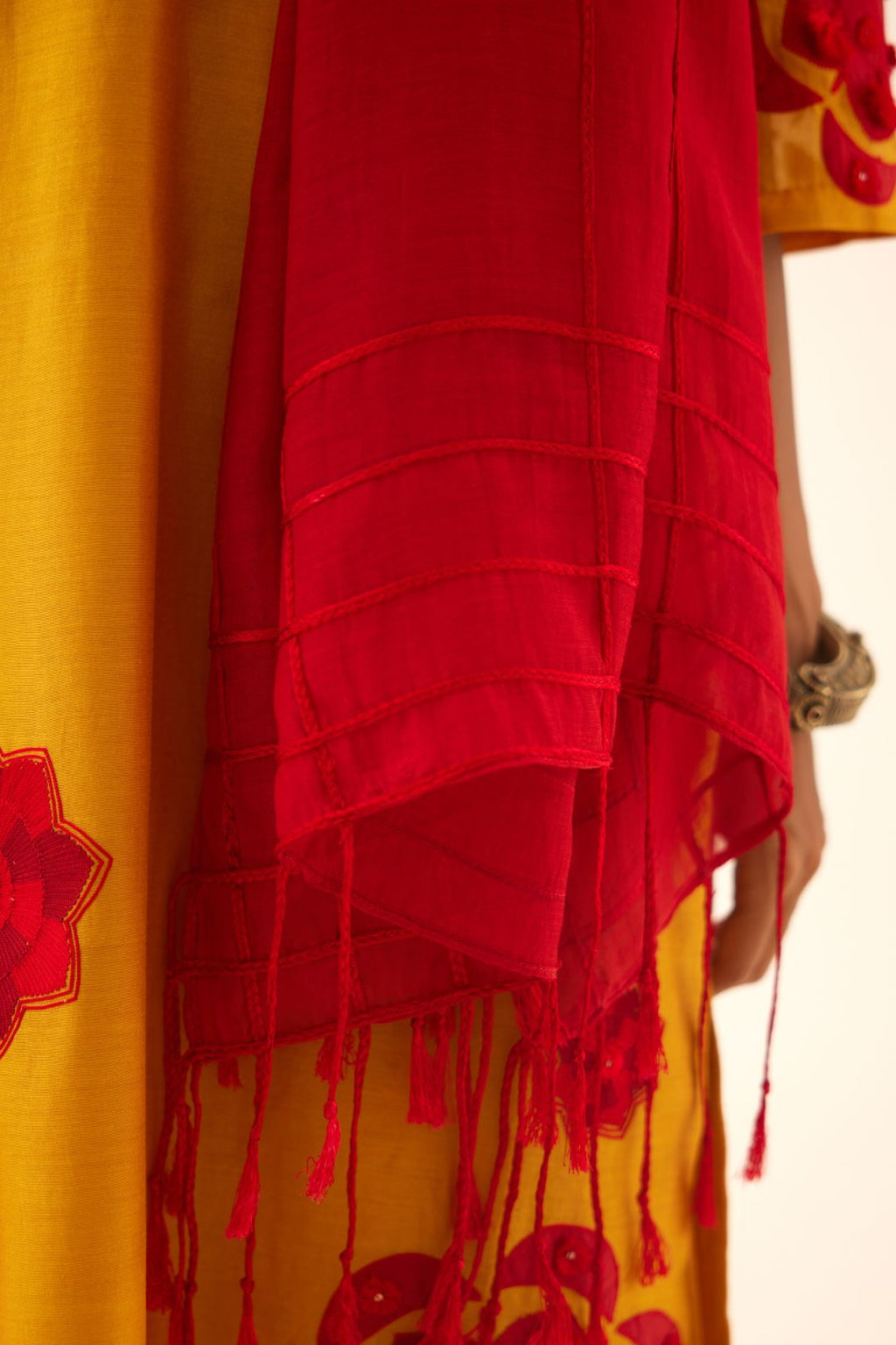 Yellow silk chanderi straight kurta set with 3/4th sleeve, highlighted with red patch, tassles & sequence work.
