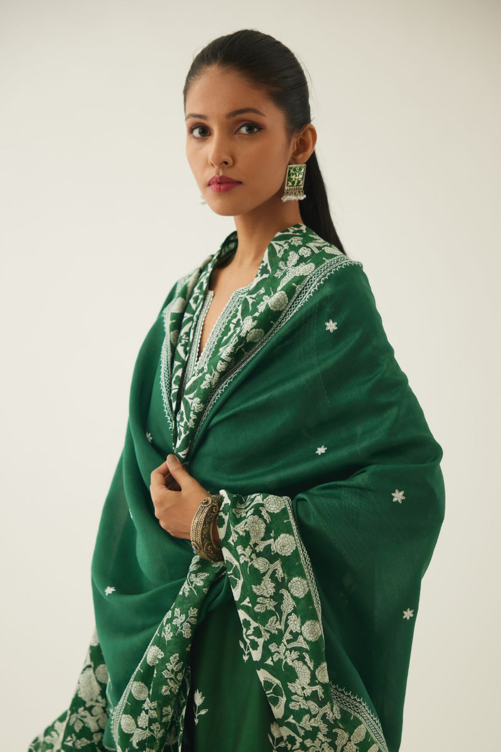 Green silk chanderi dupatta highlighted with all-over off white thread embroidery and mixed printed border running along all edges.