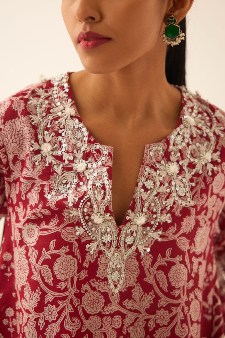 Red hand block printed short kalidar kurta set highlighted with sequins, tassels and bead work.
