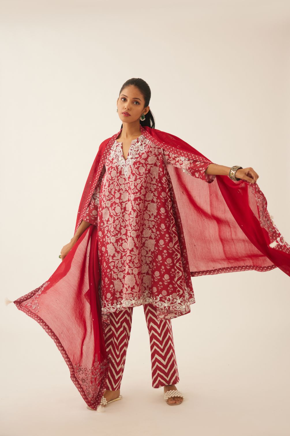 Red hand block printed short kalidar kurta set highlighted with sequins, tassels and bead work.