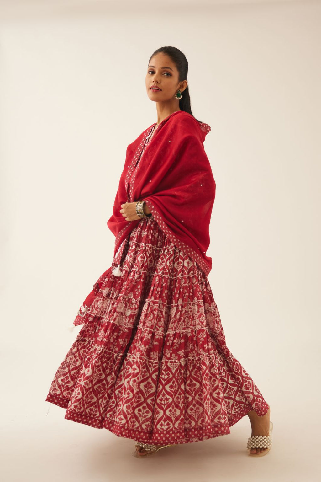Red hand block printed multi-tiered kurta dress set with 3/4 sleeves, highlighted with sequins, tassels and bead work.