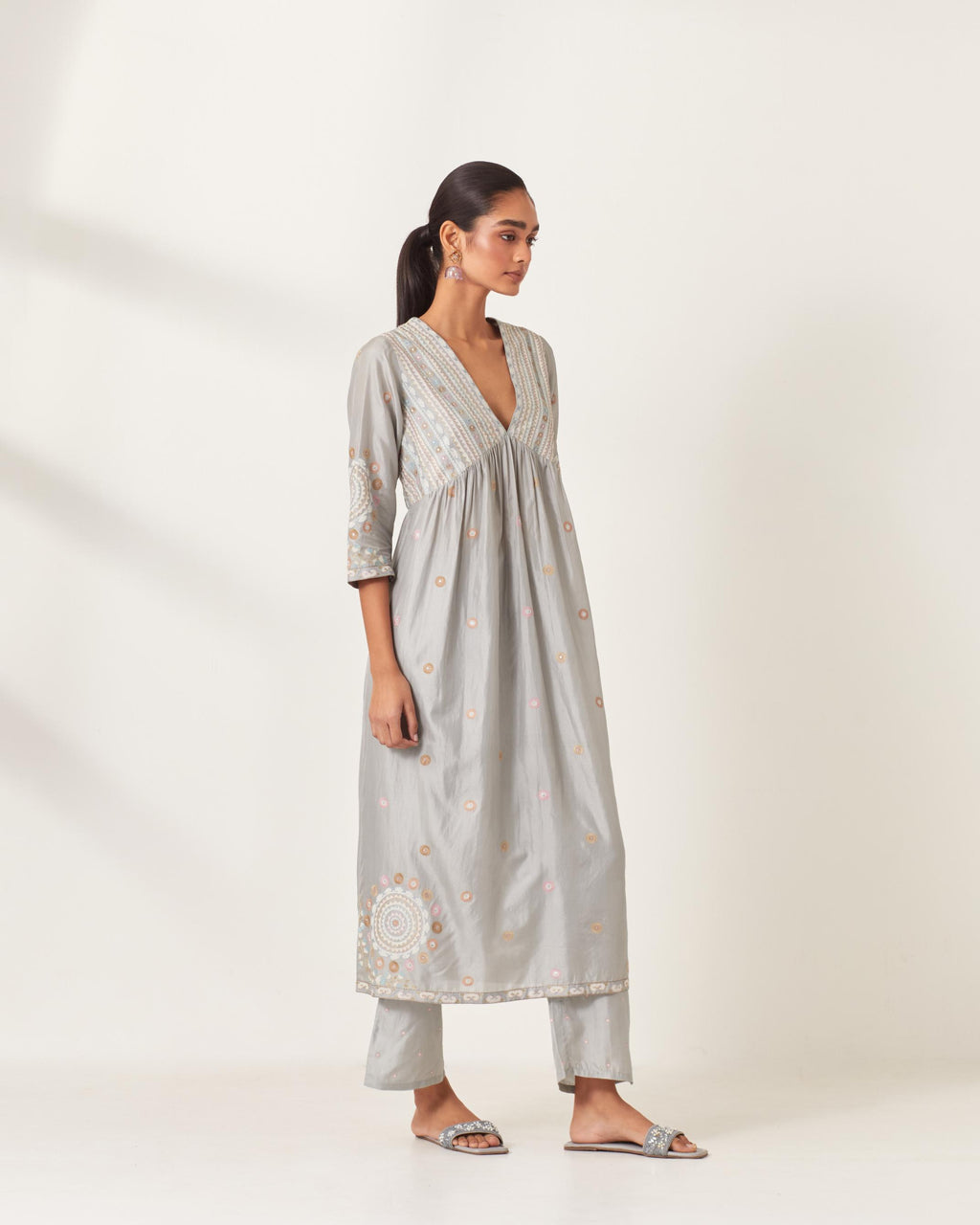Blue silk kurta dress set with appliqué stripes along with aari threadwork flowers and floral trellises along with a circular appliqued motif and fine gathers at empire line.