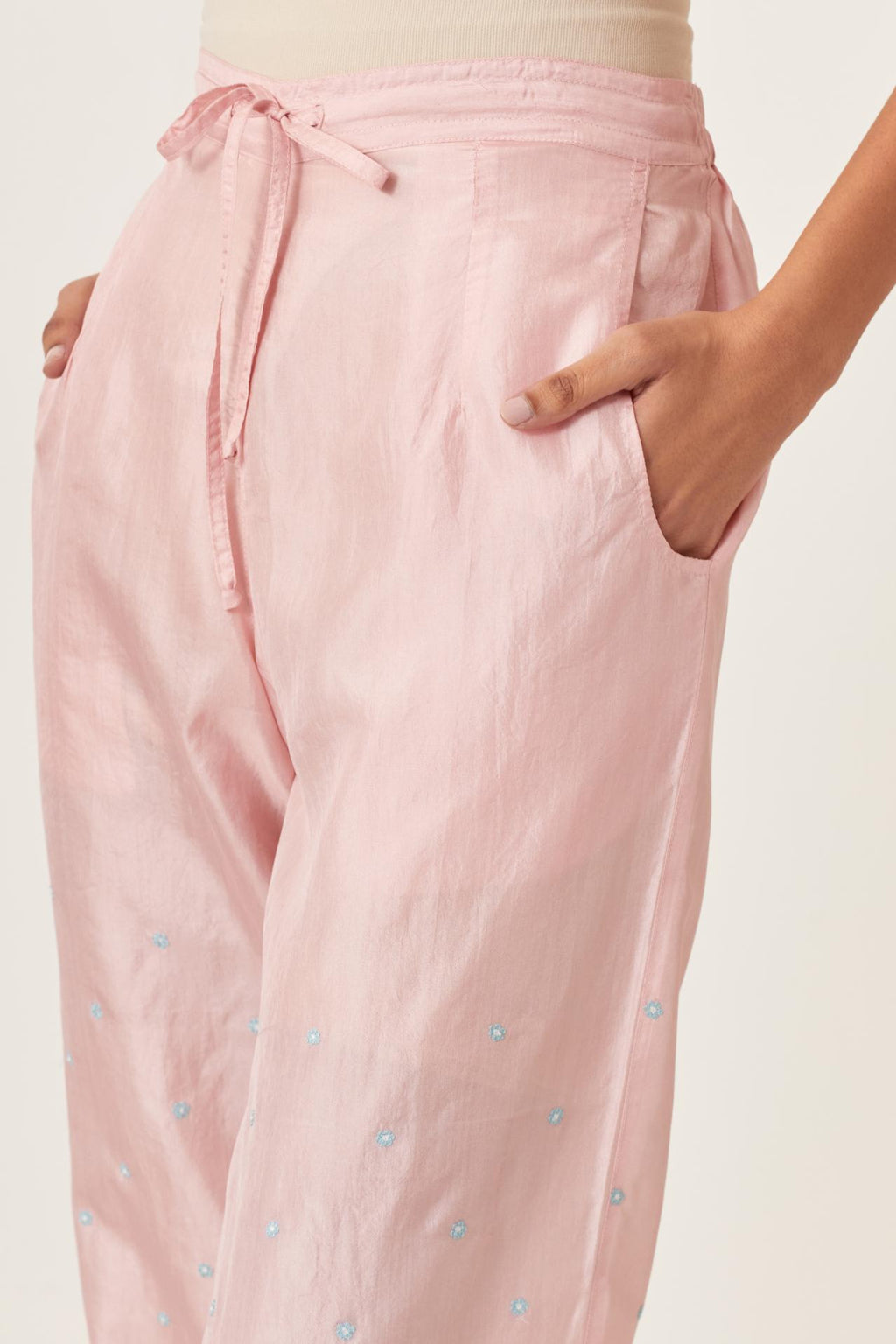 Pink silk straight pants detailed with small flower embroidery at bottom.