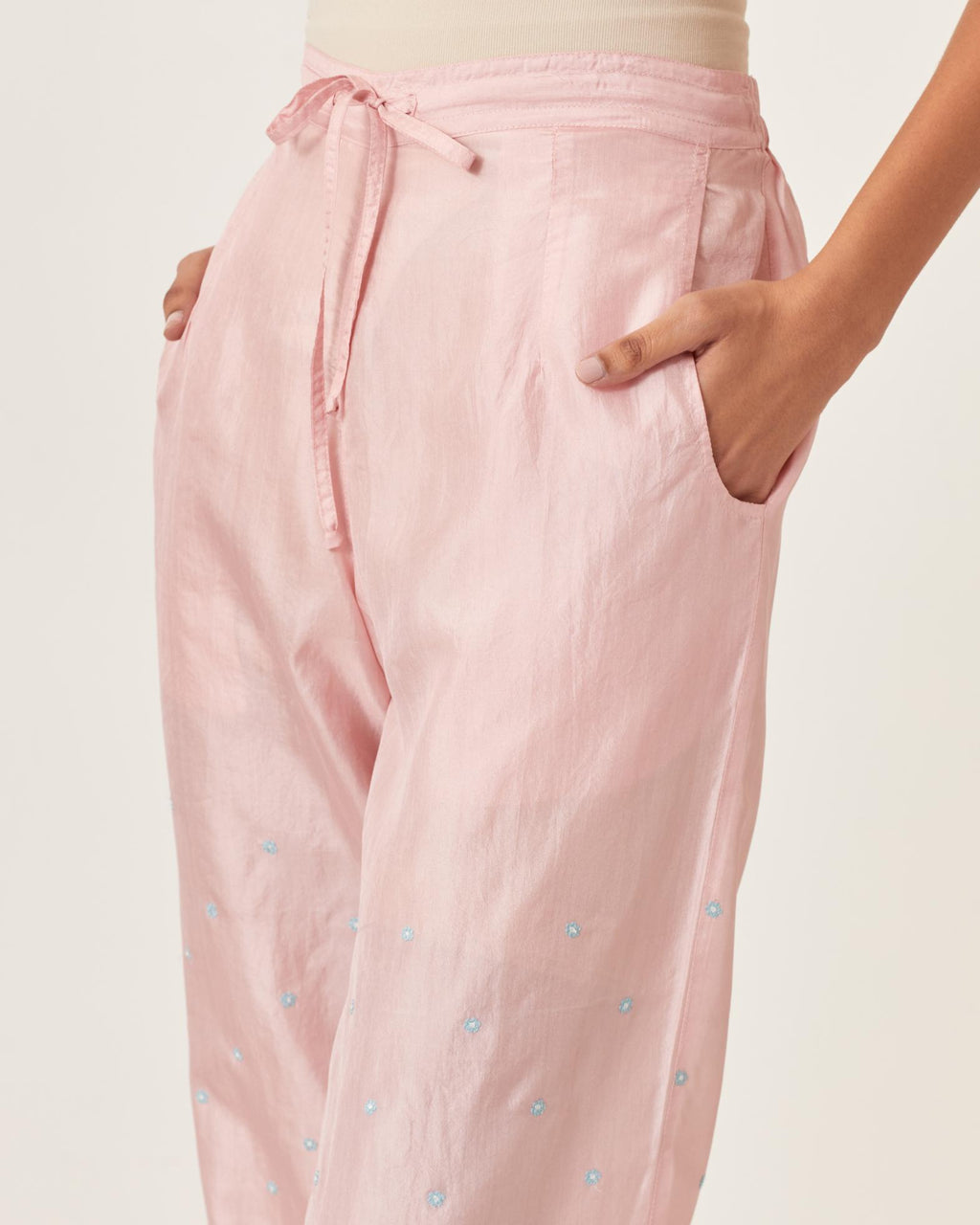 Pink silk straight pants detailed with small flower embroidery at bottom.