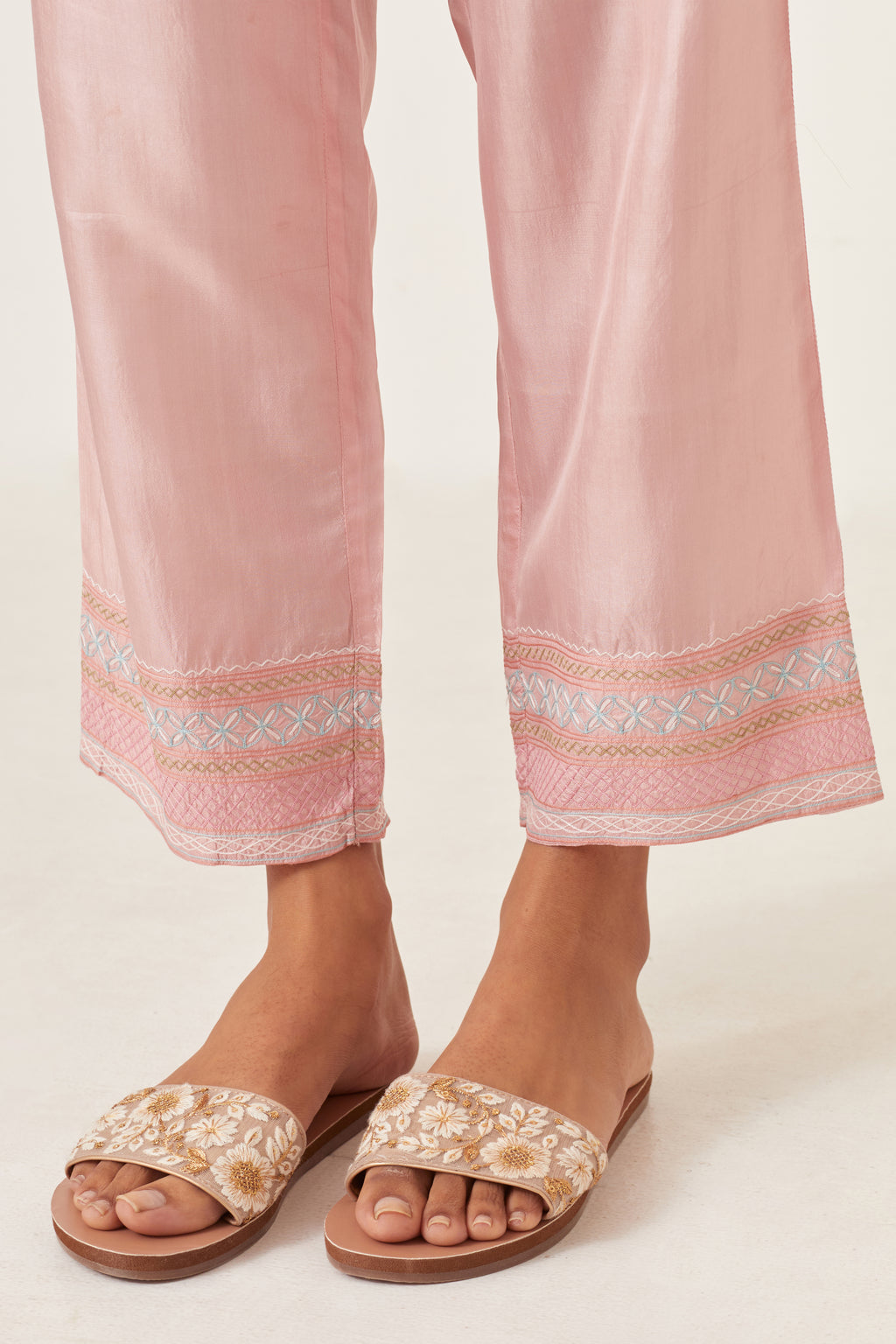 Pink silk straight pants detailed with quilted multi colored embroidery at bottom.