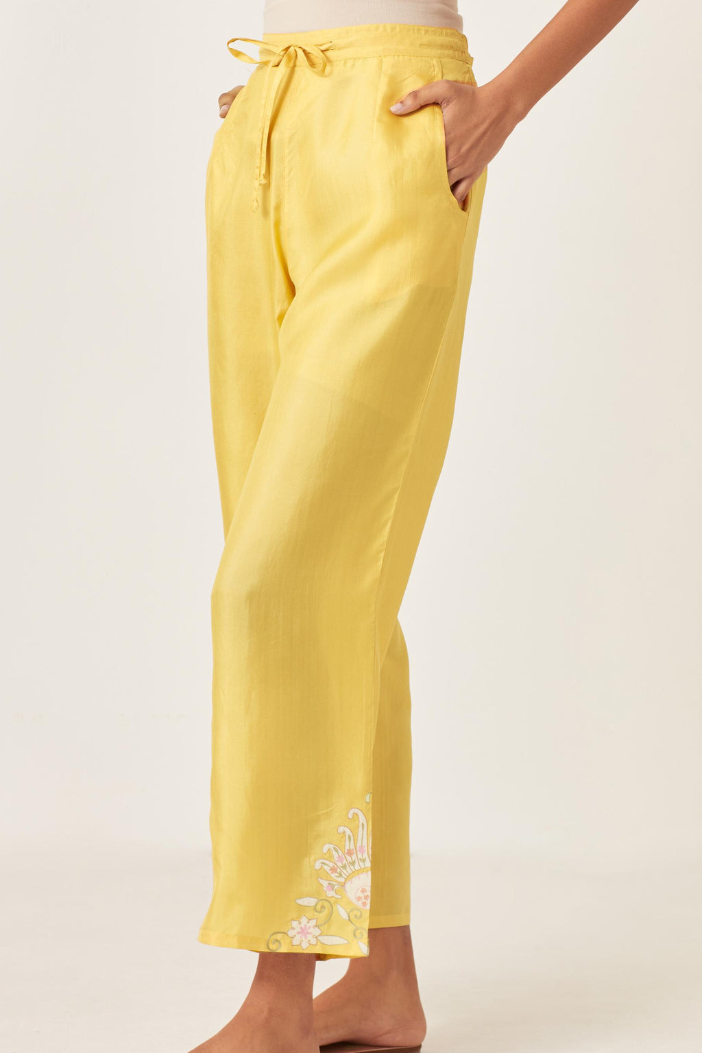 Yellow silk straight pants with multi colored appliqué at hem.